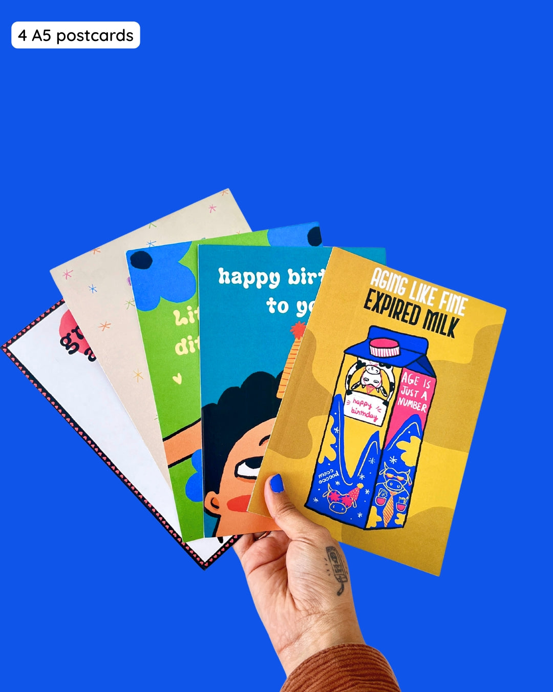 Collection of colorful postcards held against a blue background